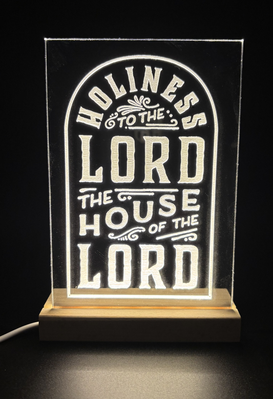 Clear Acrylic engraved with 'Holiness to the Lord, The House of the Lord' stylized after how it appears on the Salt Lake Temple.  Shown on an edge-lit wooden base.